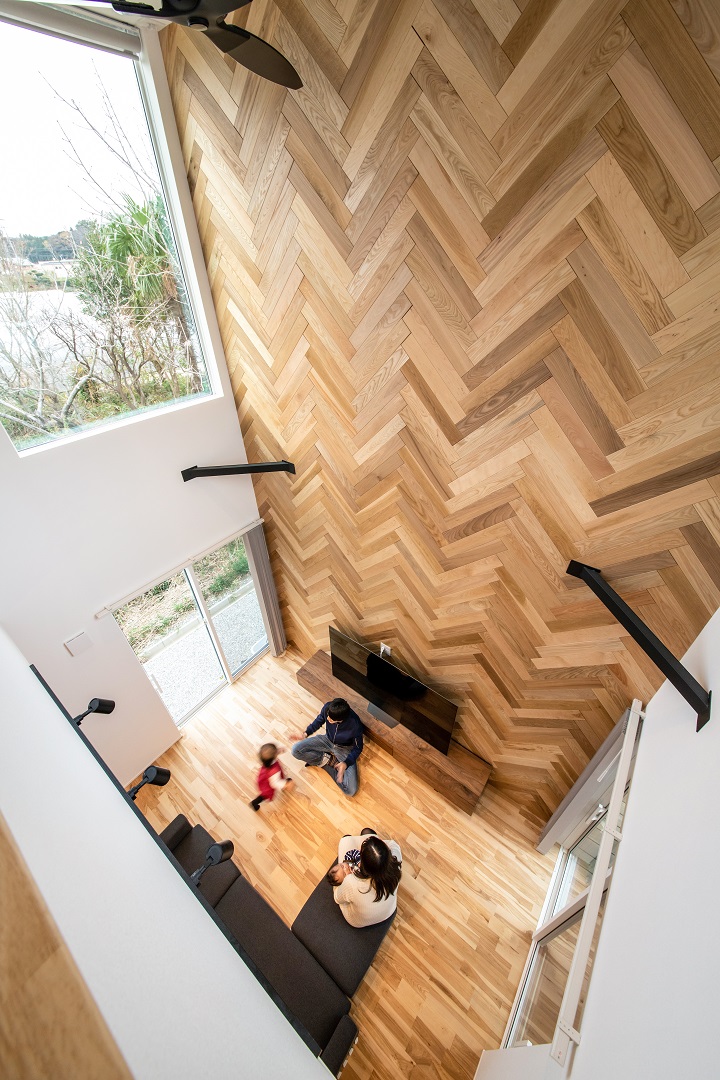 吹抜けのヘリンボーン柄の壁が印象的な家
