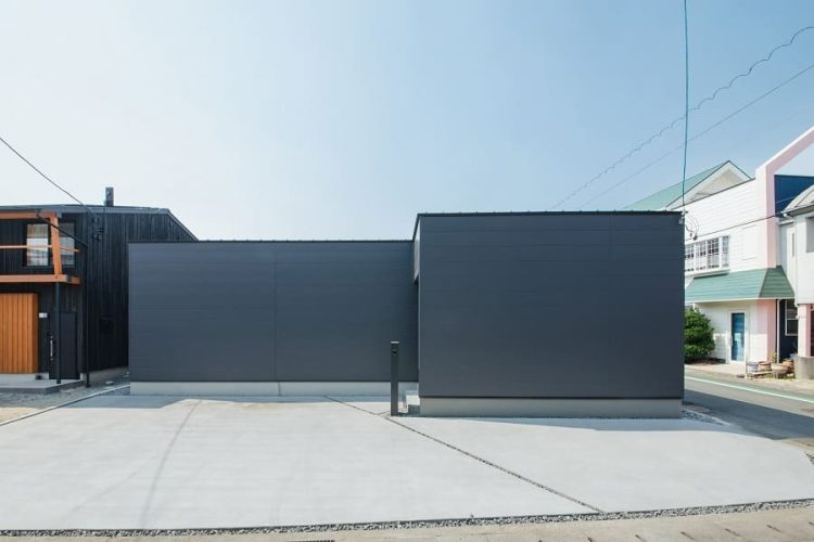 広い駐車スペースを備えた黒い箱型のシンプルモダンな外観